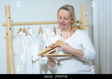camicie bianche appese su cestelli bianchi da incasso, con cassetti e altri accessori. Foto di alta qualità Foto Stock