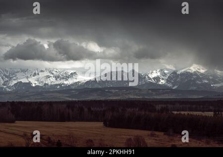Montagne luminose circondate da nuvole scure e pioggia imminente. Cielo drammatico. Vette innevate. Western Tatra, Monte Giewont, Polonia Foto Stock