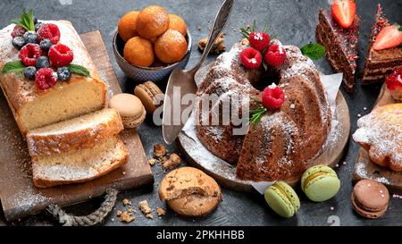 Dessert diversi su sfondo scuro. Delizioso tavolo da dessert dolce con Pound Cake, cioccolato e torte di velluto rosso. Vacanza dolce mangiare concetto. Foto Stock