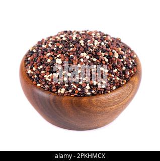 Semi di quinoa in ciotola di legno, isolati su fondo bianco. Mix di quinoa bianca, rossa e nera Foto Stock