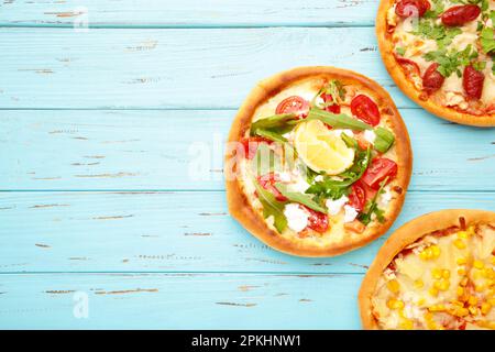 Tre diversi tipi di pizze su un tavolo di legno blu con spazio copia. Vista dall'alto Foto Stock