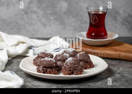 Biscotti al cocco e al cioccolato. Prodotti da forno. Biscotti con tè su sfondo scuro Foto Stock