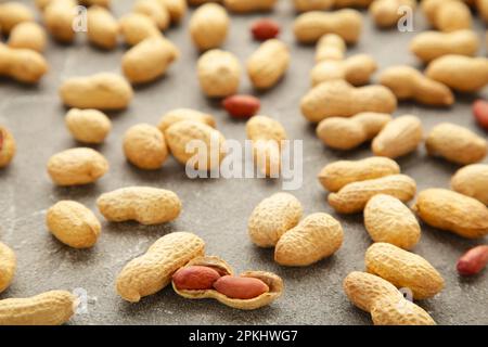 Molte arachidi in conchiglie su fondo grigio cemento. Struttura del cibo. Vista dall'alto Foto Stock