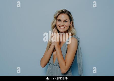 Amichevole bella giovane donna bionda indossare romantico abito estivo con fidato angelo posizione, tenendo le mani in gesto di preghiera, sorridente e askin Foto Stock