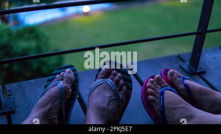 Gambe di coppia in pantofole sul balcone di notte Foto Stock