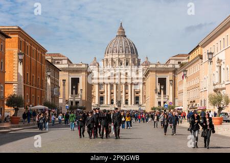 ROM, Italien, Apr. 2023 Vatikanstadt blick über die Via della conciliazione zum Petersdom mit seiner imposanten Kuppel, im Vordergrund eine Gruppe Car Foto Stock