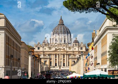 ROM, Italien, Apr. 2023 Vatikanstadt blick über die Via della conciliazione zum Petersdom mit seiner imposanten Kuppel, im Vordergrund eine Gruppe Car Foto Stock