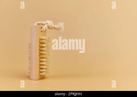 Spazzola in legno per massaggio corpo secco anticellulite, scrub in fibra di bambù ecologica. Cura del corpo a casa. Sfondo beige, spazio copia Foto Stock