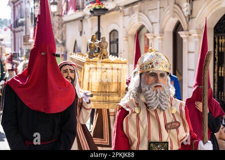 Puente Genil, Spagna. 07th Apr, 2023. Un Nazareno che indossa un cappello a forma di cono accompagna i personaggi biblici vestiti come Israeliti che portano l'Arca dell'Alleanza durante una processione del Venerdì Santo, parte della settimana Santa o Semana Santa, 7 aprile 2023 a Puente Genil, Spagna. La città ha una celebrazione insolita con una processione di tutte le figure bibliche dal 1661. Credit: Richard Ellis/Richard Ellis/Alamy Live News Foto Stock