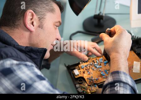 l'uomo ripara i componenti elettronici Foto Stock