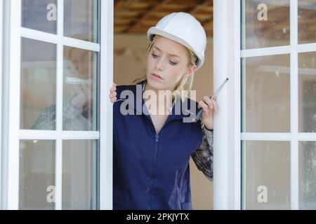 ingegnere costruttore femmina che fissa una finestra Foto Stock