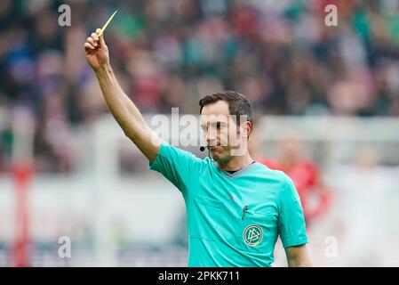 Magonza, Germania. 08th Apr, 2023. Calcio: Bundesliga, FSV Mainz 05 - Werder Bremen, Giornata 27, Mewa Arena. L'arbitro Benjamin Brand mostra il cartellino giallo. Credit: Uwe Anspach/dpa - NOTA IMPORTANTE: In conformità ai requisiti della DFL Deutsche Fußball Liga e del DFB Deutscher Fußball-Bund, è vietato utilizzare o utilizzare fotografie scattate nello stadio e/o della partita sotto forma di sequenze di immagini e/o serie di foto simili a video./dpa/Alamy Live News Foto Stock