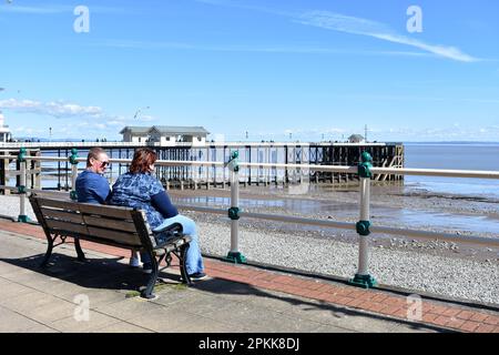 Coppia seduta su panchina vicino al molo di Penarth, Penarth, Galles Foto Stock