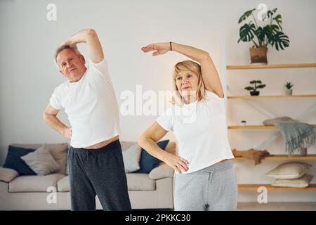 Fare stretching. L'uomo anziano e la donna sono insieme a casa. Foto Stock
