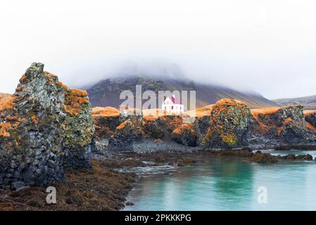 Casa solitaria sopra la scogliera basaltica vicino al porto, Arnarstapi, Parco Nazionale di Snaefelsjokull, penisola di Snaefelsness Foto Stock