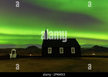 La chiesa di Budakirkja in legno nero sotto l'aurora boreale verde e la notte stellata, Budir, Penisola della Notturno Foto Stock