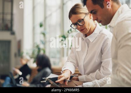 Due colleghi collaboratori che lavorano insieme per un nuovo piano aziendale durante la giornata lavorativa in ufficio Foto Stock