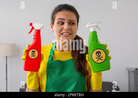 Donna che mostra bottiglie di sostanze chimiche tossiche per la casa con segnali di avvertimento, primo piano Foto Stock