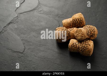 Tappi di vino frizzante con immagini d'uva su tavola nera. Spazio per il testo Foto Stock