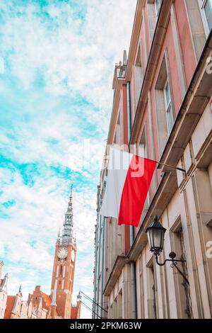 Polonia bandiera in cielo blu e il centro di Danzica sullo sfondo Foto Stock