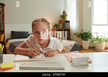 Studentessa che fa i compiti a casa alla scrivania nella sua camera da letto Foto Stock