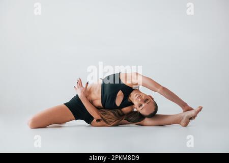 Tendendo al lato. Giovane donna in abiti sportivi che fanno ginnastica in interni. Foto Stock