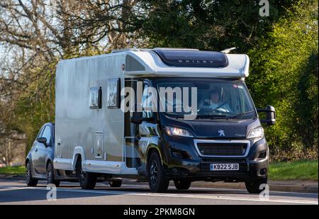 2022 PEUGEOT BAILEY AUTOGRAPH III 79-4F camper trainante una Fiat 500 che viaggia su una strada di campagna inglese Foto Stock