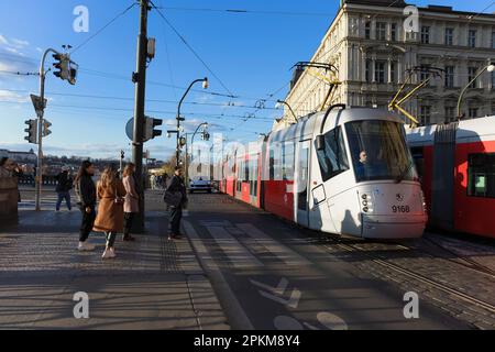 Praga, Repubblica Ceca - 4 aprile 2023: Tram e tram sulla strada. Trasporto pubblico nella capitale. Pedoni sul marciapiede, auto sul Foto Stock