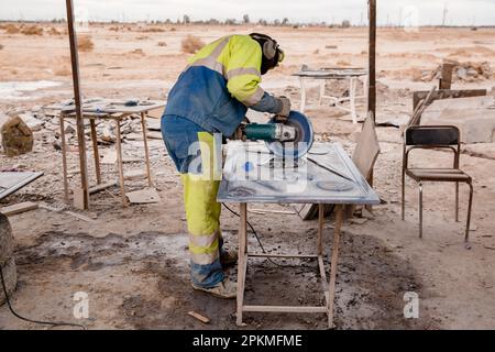 Un uomo marocchino lavora con una lucidatrice di pietra Foto Stock
