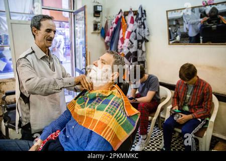 Un turista americano che ottiene un rasoio diritto in un barbiere a Marrakech Marocco Foto Stock