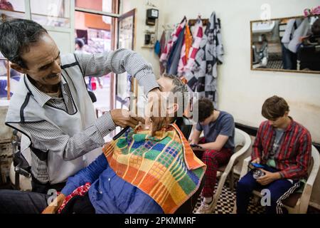 Un turista americano che ottiene un rasoio diritto in un barbiere a Marrakech Marocco Foto Stock