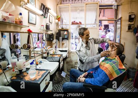 Un turista americano che ottiene un rasoio diritto in un barbiere a Marrakech Marocco Foto Stock