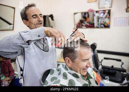 Un turista americano ottenere un taglio di capelli in un barbiere a Marrakech Marocco Foto Stock