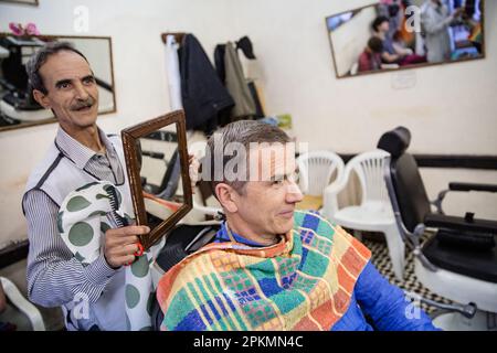 Un turista americano guarda in uno specchio dopo aver fatto un rasoio dritto e un taglio di capelli in un barbiere a Marrakech Marocco Foto Stock