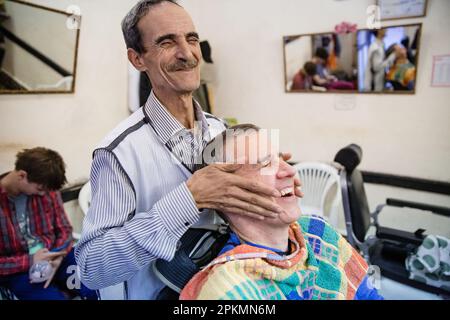 Un turista americano che ottiene un rasoio diritto e un taglio di capelli in un barbiere a Marrakech Marocco Foto Stock
