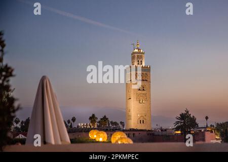 Vista serale della Moschea di Koutoubia dal bar sul tetto dell'hotel El Fenn a Marrakech, Marocco Foto Stock