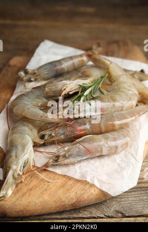 Gamberetti freschi crudi con rosmarino su tavola di legno Foto Stock