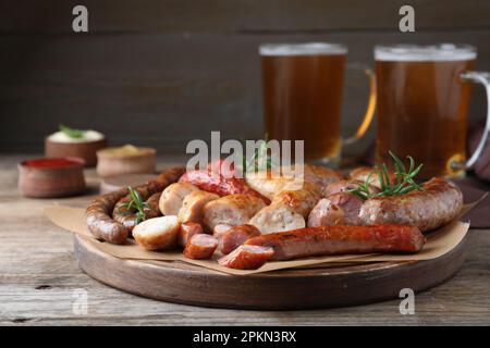 Set di gustosi spuntini e birra diversi sul tavolo di legno Foto Stock