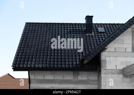 Casa incompiuta con tetto nero contro il cielo blu Foto Stock