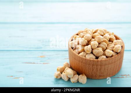 Ceci secchi non cotti in una ciotola di legno su fondo blu. Concetto di cibo vegano. Vista dall'alto Foto Stock