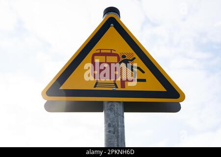 Segnale di avvertimento giallo triangolare sulla piattaforma che indica attenzione ai treni in arrivo e in transito Foto Stock