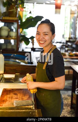 Cameriera felice vietnamita che lavora in una cucina di un caffè Foto Stock