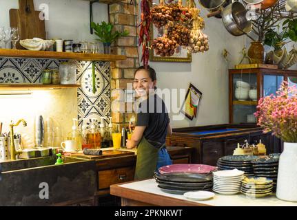 Cameriera felice vietnamita che lavora in una cucina di un caffè Foto Stock