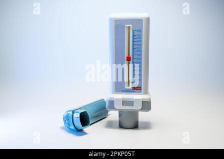 Misuratore di picco di flusso e un inalatore blu, dispositivi medici per pazienti con allergia all'asma o BPCO, sfondo grigio chiaro con spazio di copia, focus selezionato, n Foto Stock