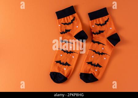 Calzini arancioni con pipistrelli. Costume di abbigliamento per la festa di Halloween. Vista dall'alto della calza vivace e multicolore. Spazio di copia. Foto Stock