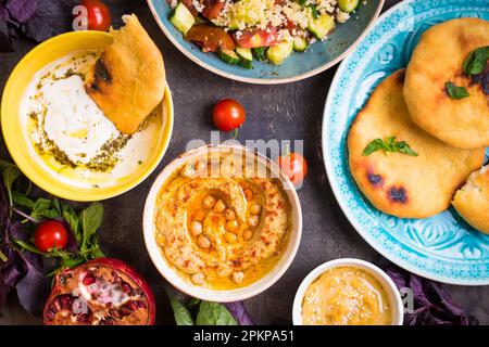 Tabella servita con medio orientali tradizionali piatti vegetariani. Hummus, la tahina, pitta, cuscus insalata e latticello dip con olio di oliva. Cena di gala Foto Stock