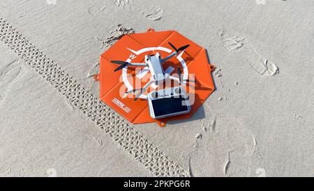 Fire Island, New York, USA - 20 febbraio 2023: Drone DJI mini pro 3 su un take off pad arancione con il suo controller sulla sabbia in spiaggia. Foto Stock