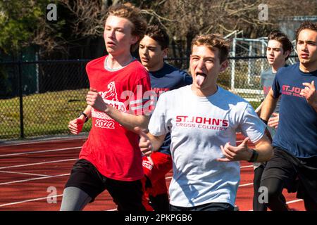 West Islip, New York, USA - 4 aprile, 2023: Vista frontale di un corridore che dà il segno sciolto appeso con entrambe le mani e che sporge la lingua durante la corsa Foto Stock