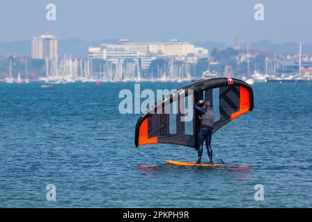 Sandbanks, Poole, Dorset UK. 9 aprile 2023. Clima nel Regno Unito: Caldo e soleggiato a Sandbanks a Poole, mentre gli amanti degli sport acquatici e gli appassionati si dirigono verso il mare per godersi le loro attività sull'acqua al sole. Oggi, domenica di Pasqua, è previsto che sia il giorno più caldo dell'anno finora con le previsioni di pioggia domani. Aletta di alare di bordo in azione - alare di bordo alare di bordo alare di surf alare di surf alare di surf alare di surf alare di surf alare di surf alare di surf alare di surf alare di mare. Crediti: Carolyn Jenkins/Alamy Live News Foto Stock