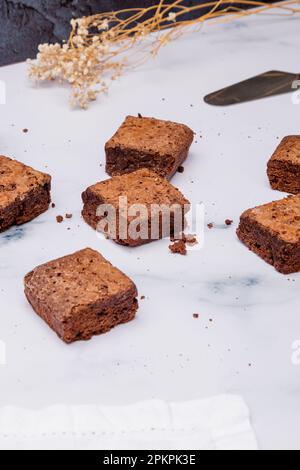 I pezzi quadrati appena sfornati di brownie al cioccolato su un tavolo di marmo Foto Stock